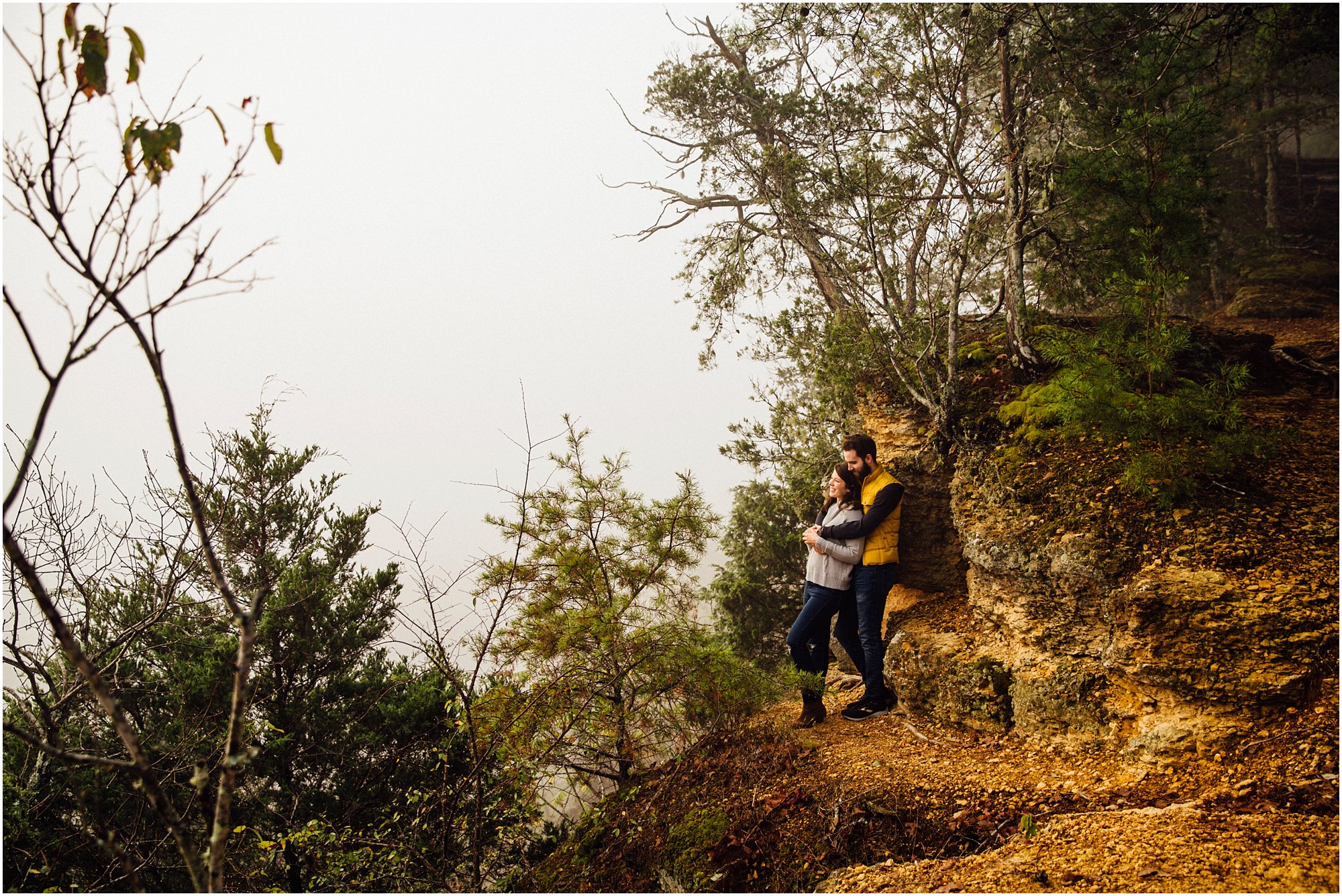 Engagement session couple leaning again cliff wall looking out into the fog in Nashville, Tennessee