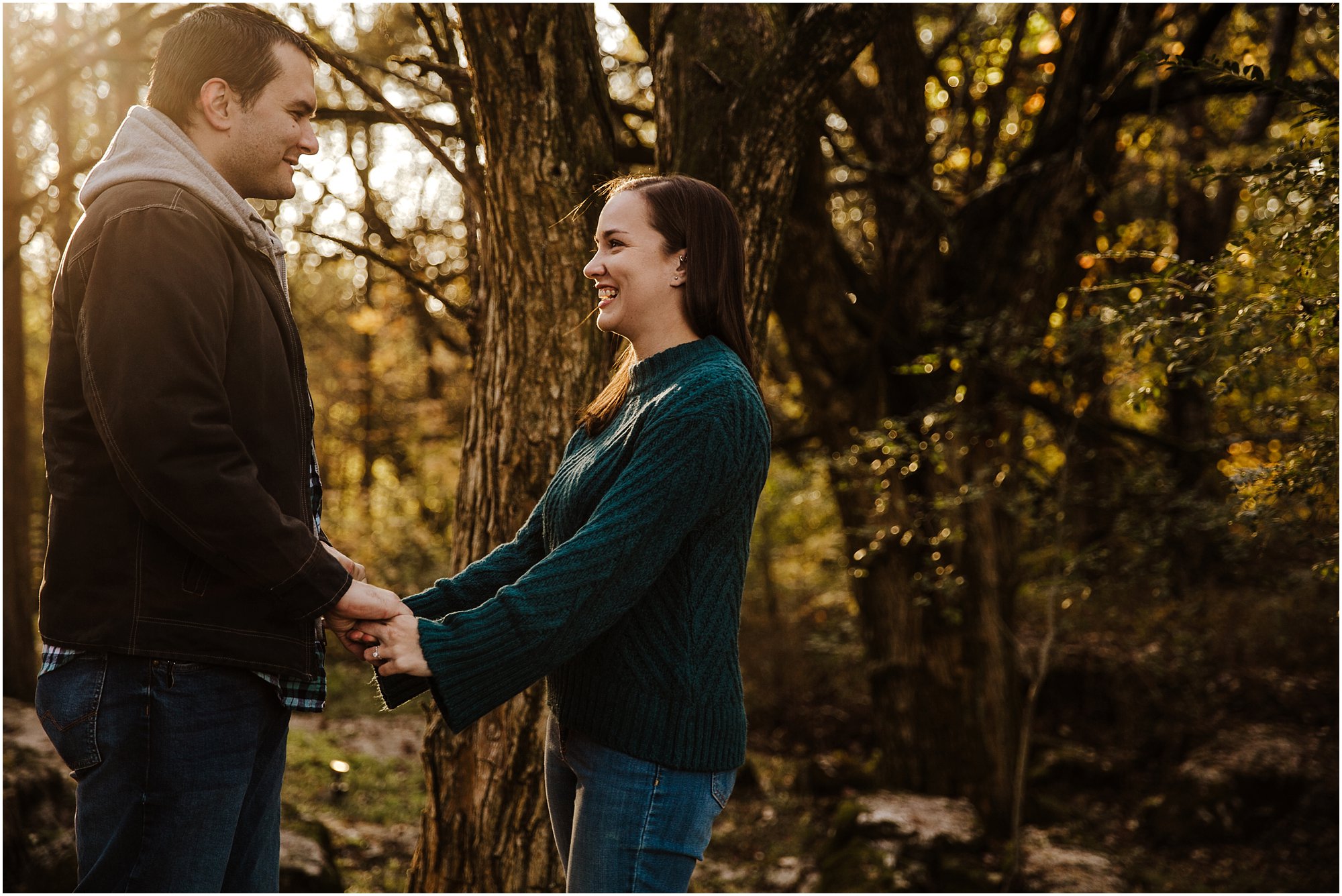 Cute couple holding hands and laughing with each other during fall engagement session
