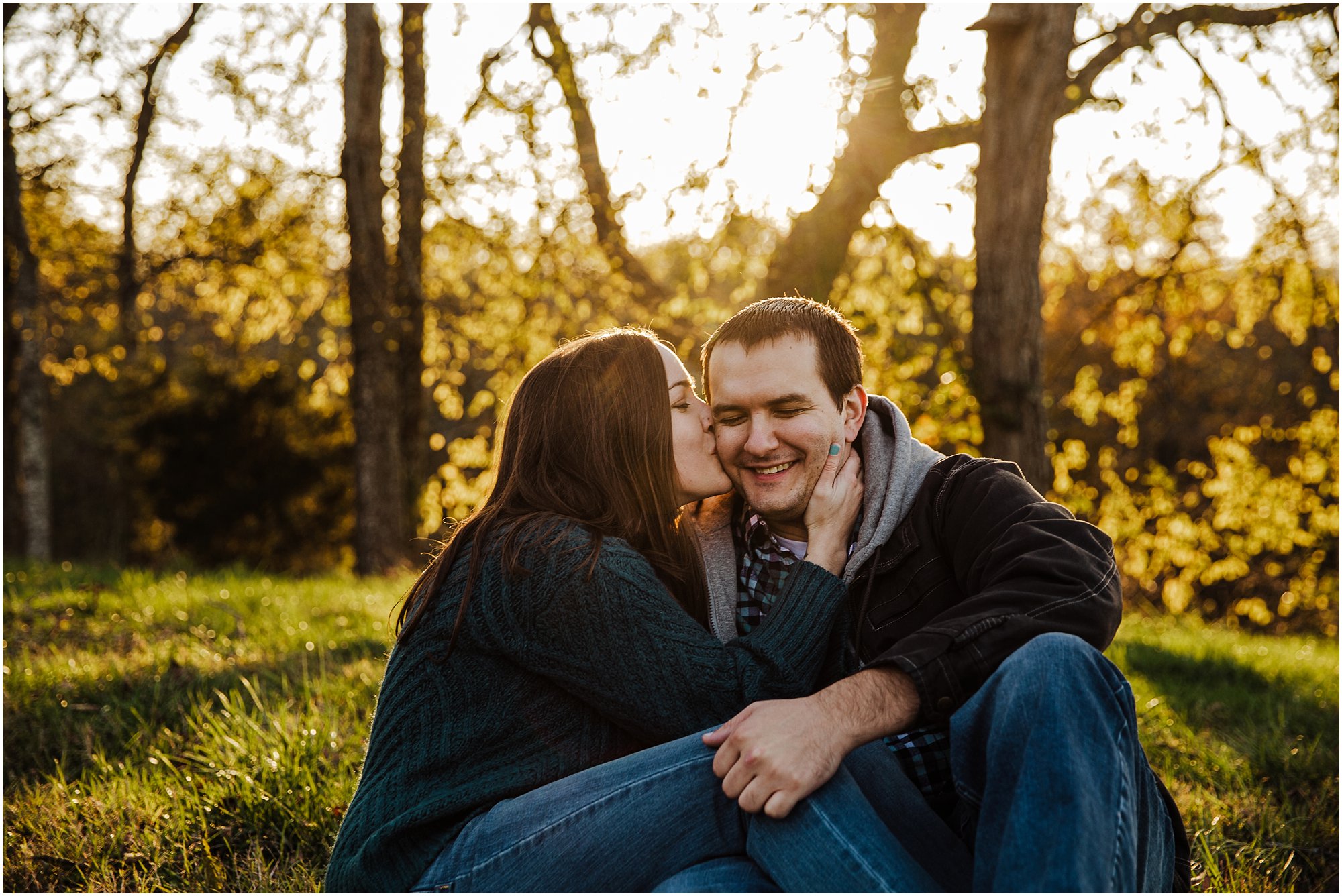 Girl kissing her fiancé on the cheek as he laughs and holds onto her.