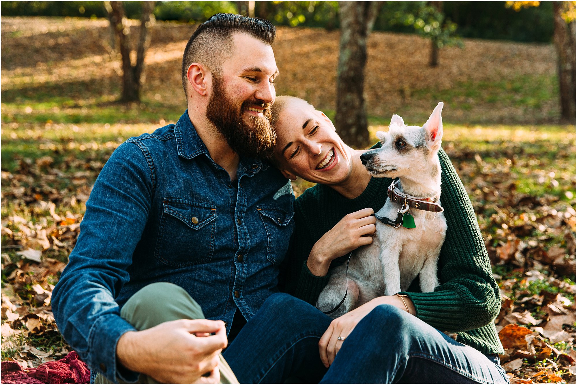 Couple smiling and laughing while they snuggle with their puppy at Deerwood Arboretum