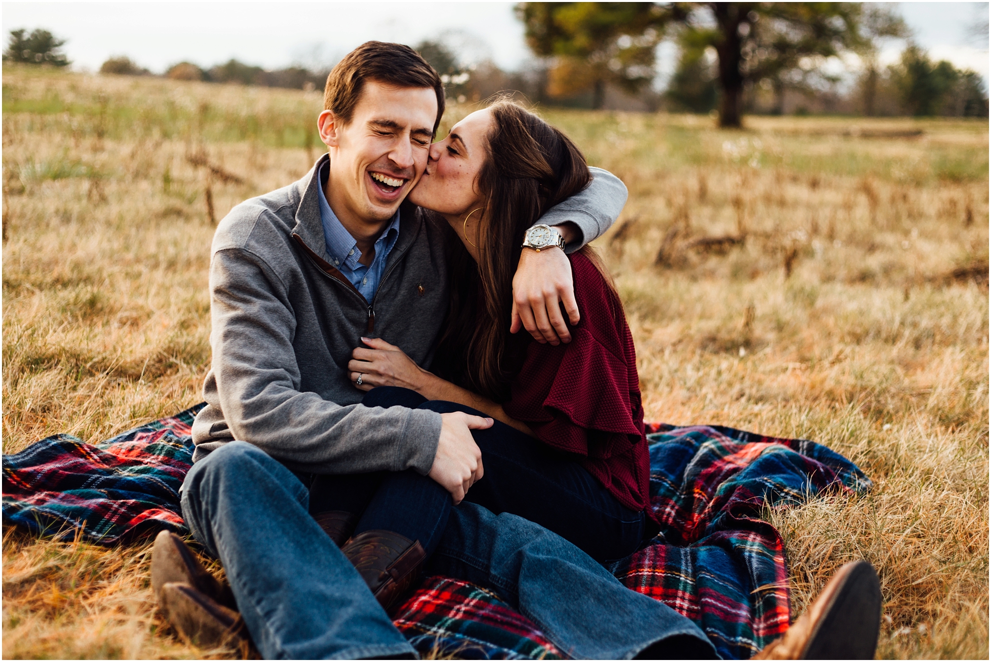 Smiling Laughing couple on blanket in a field during engagement session in Franklin, TN