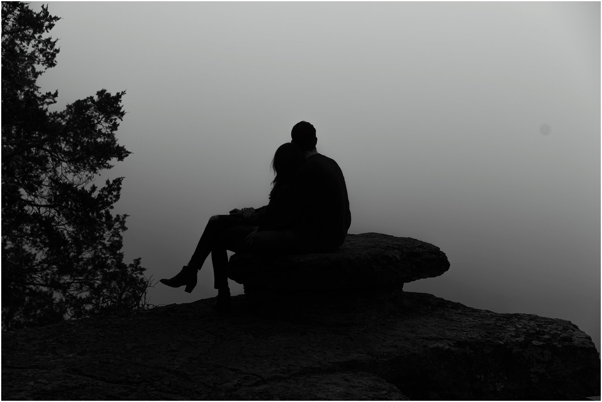 Couple sitting on overlook rock looking out into the fog at Narrows of the Harpeth
