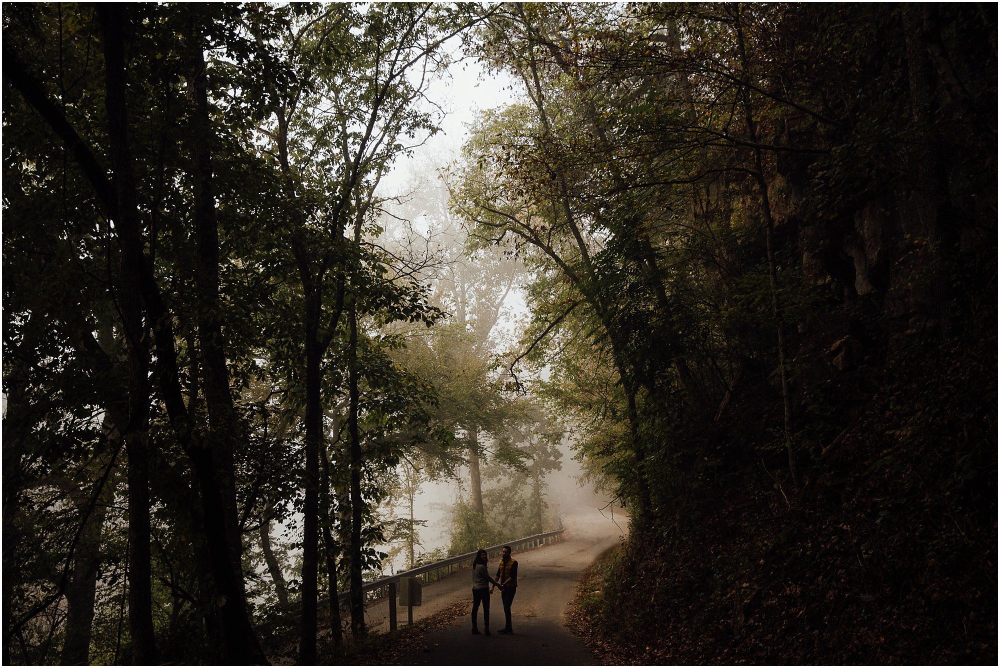 Far away shot of couple holding hands and walking down foggy road in Nashville, Tennessee.