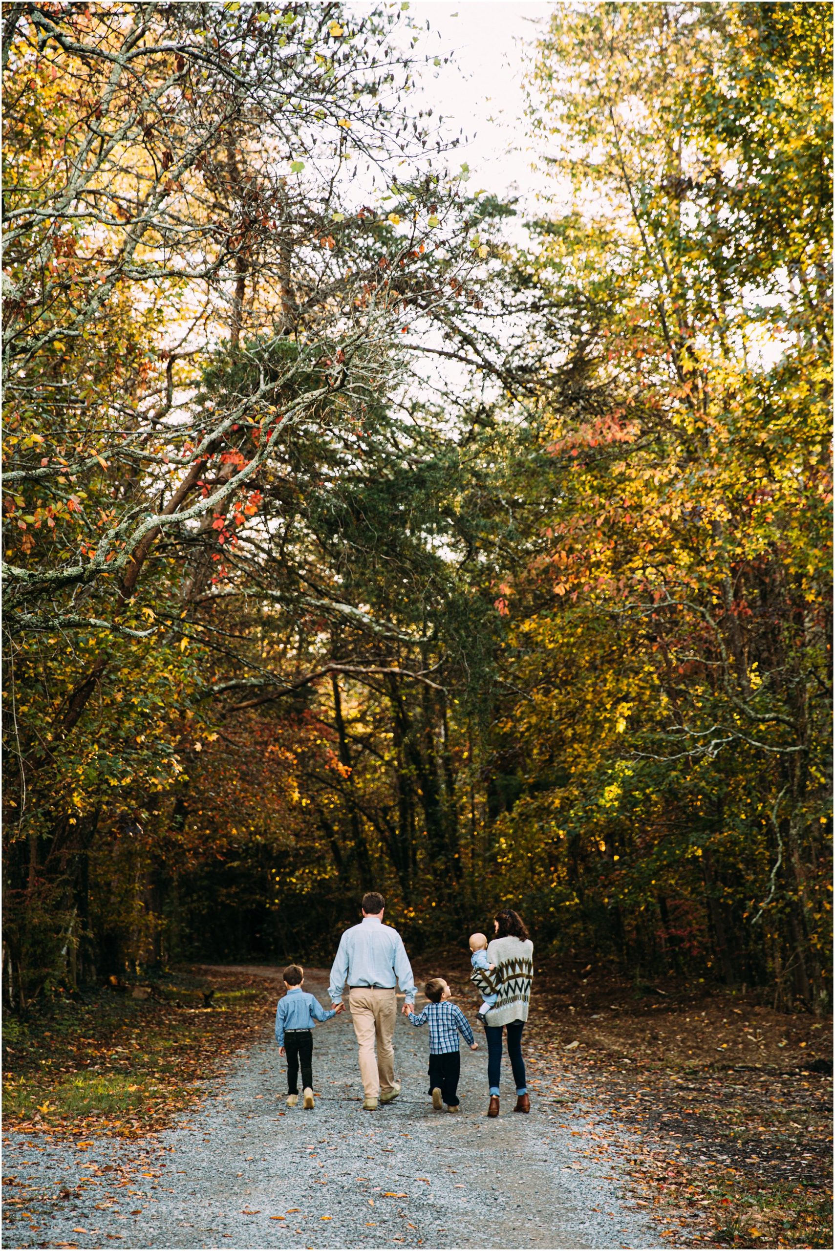 Family of five walking down gravel path under autumn trees in Chattanooga