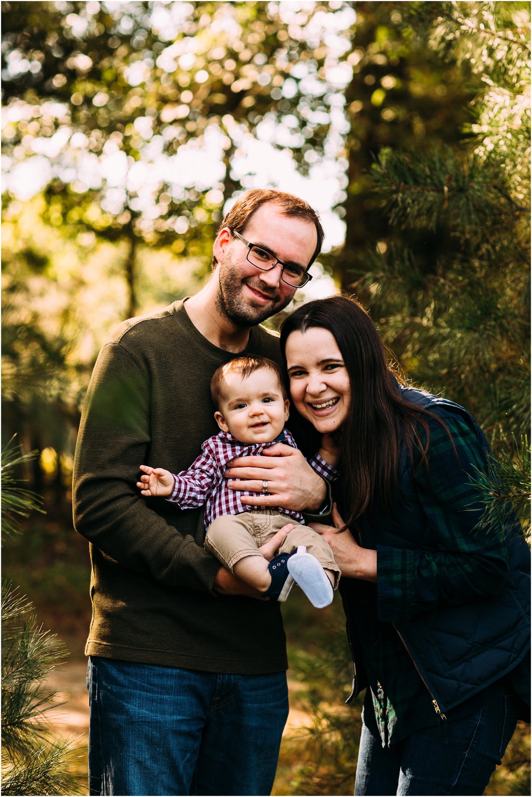 Family of three smiling together in a christmas tree farm in memphis