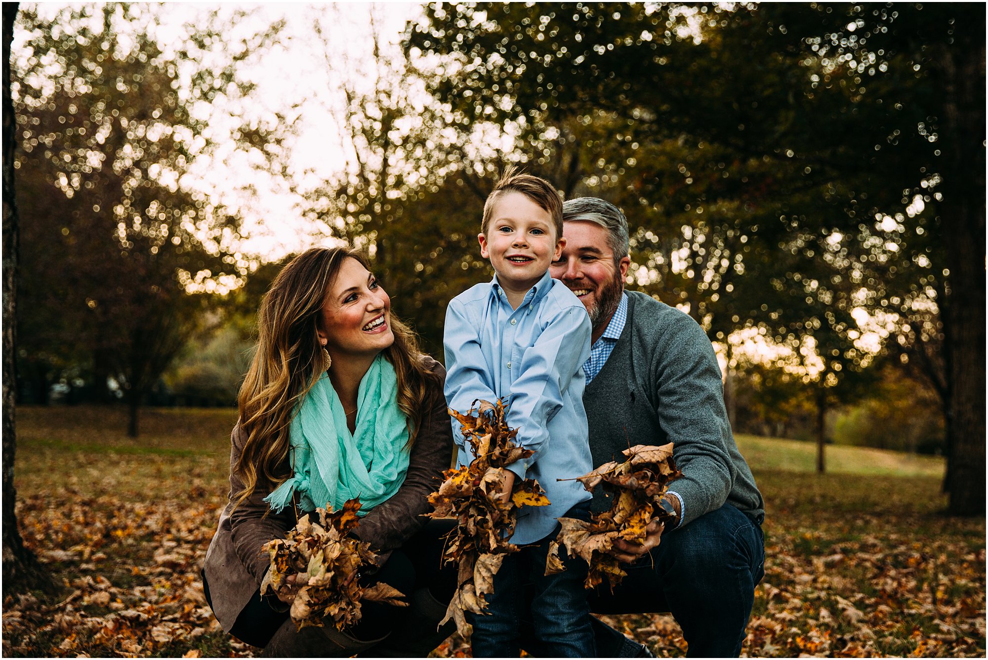 Family of three throwing fall leaves up together