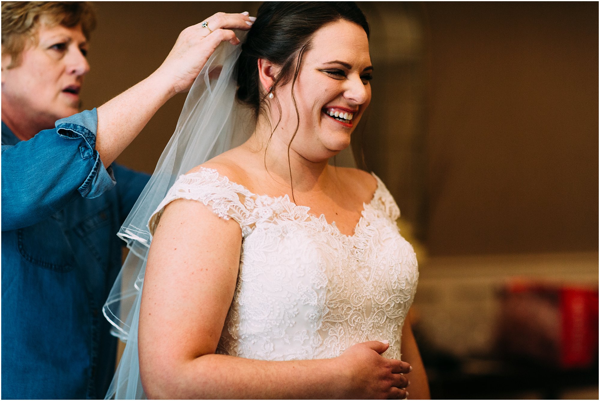 Bride Lauren laughing while veil is being put on 