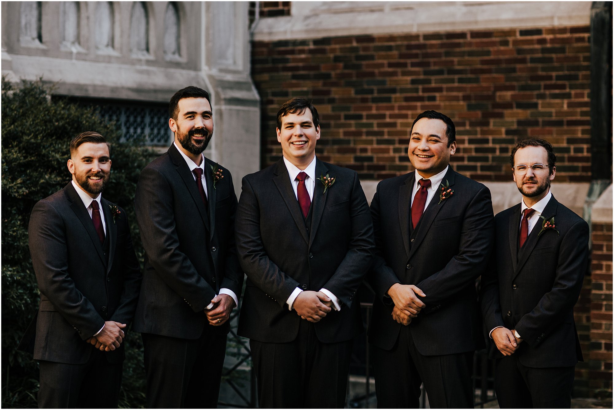 Groom and groomsmen laughing and smiling during portraits outside of historic church