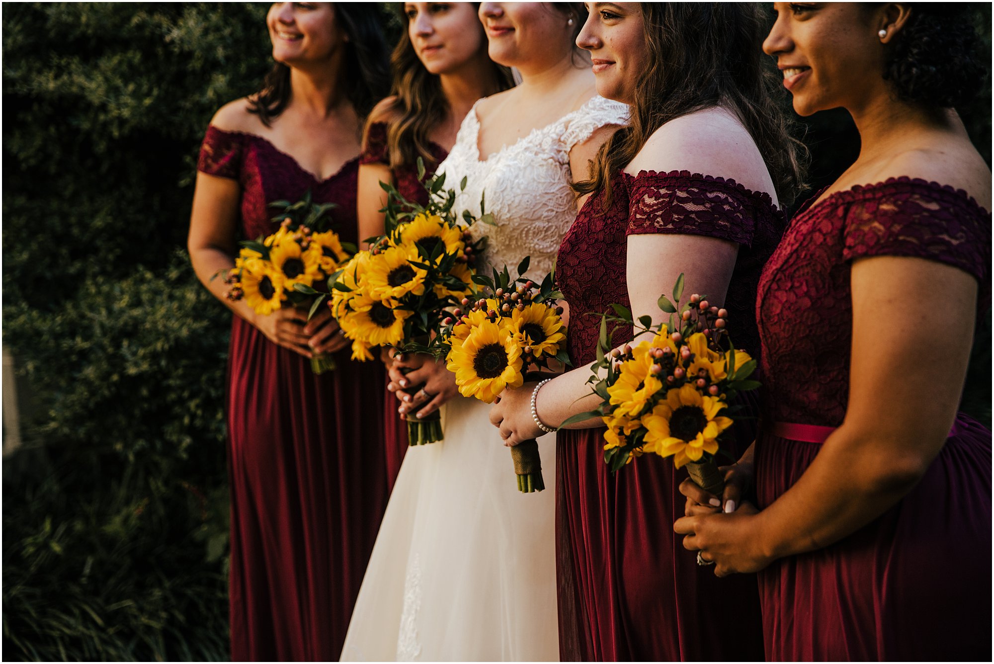Sunflower bouquets held by bridesmaids in maroon dresses