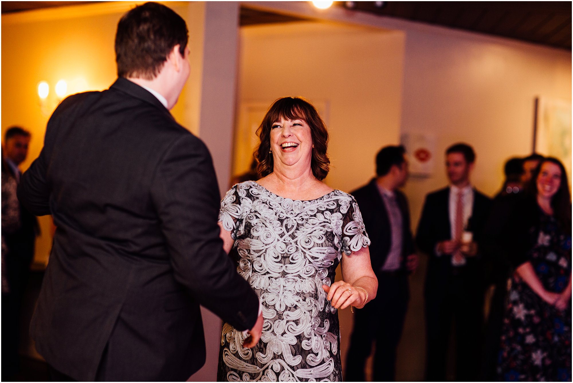 Mother laughing with her son during their dance together at his wedding