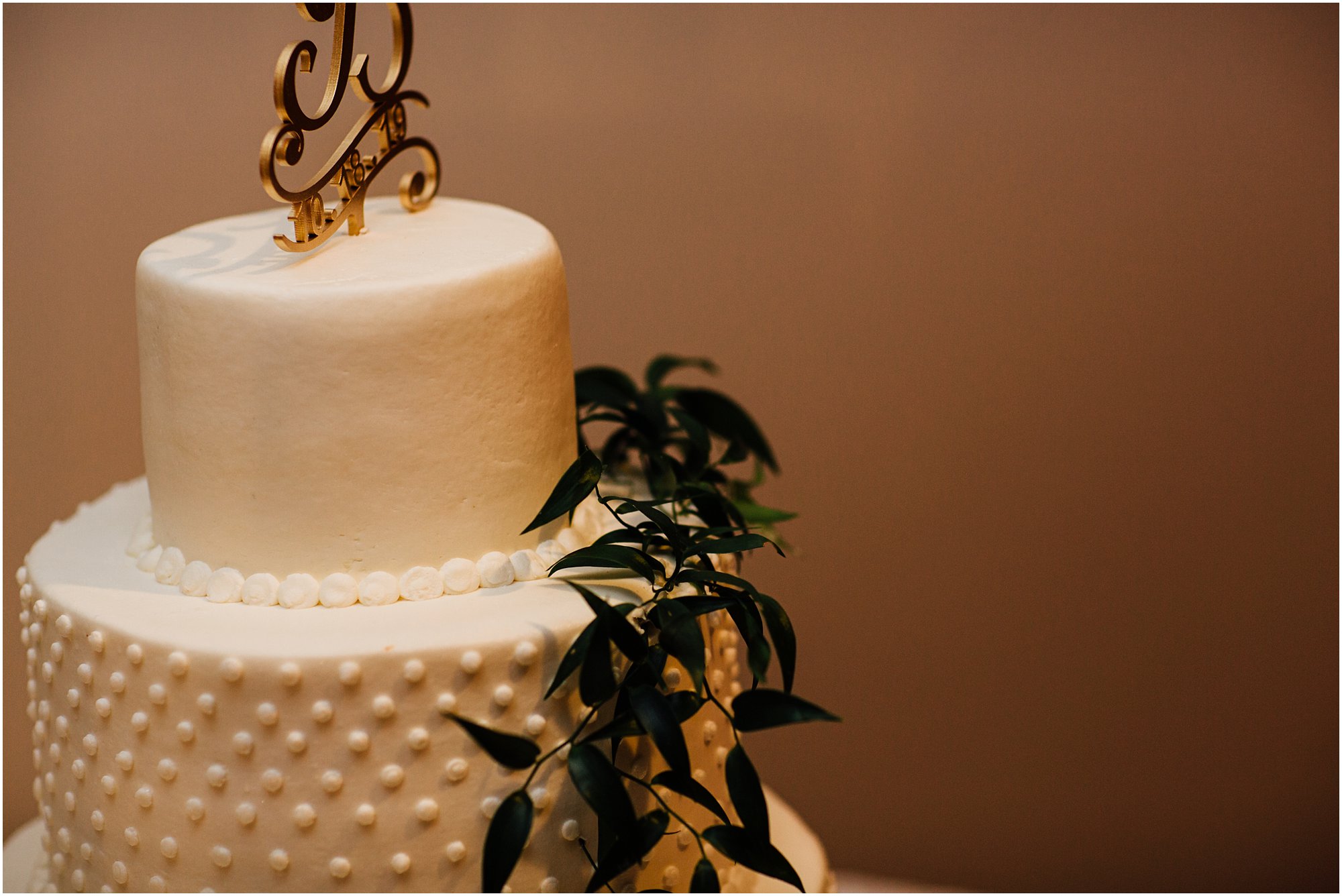 Detail shot of white wedding cake with greenery on it at Club Windward