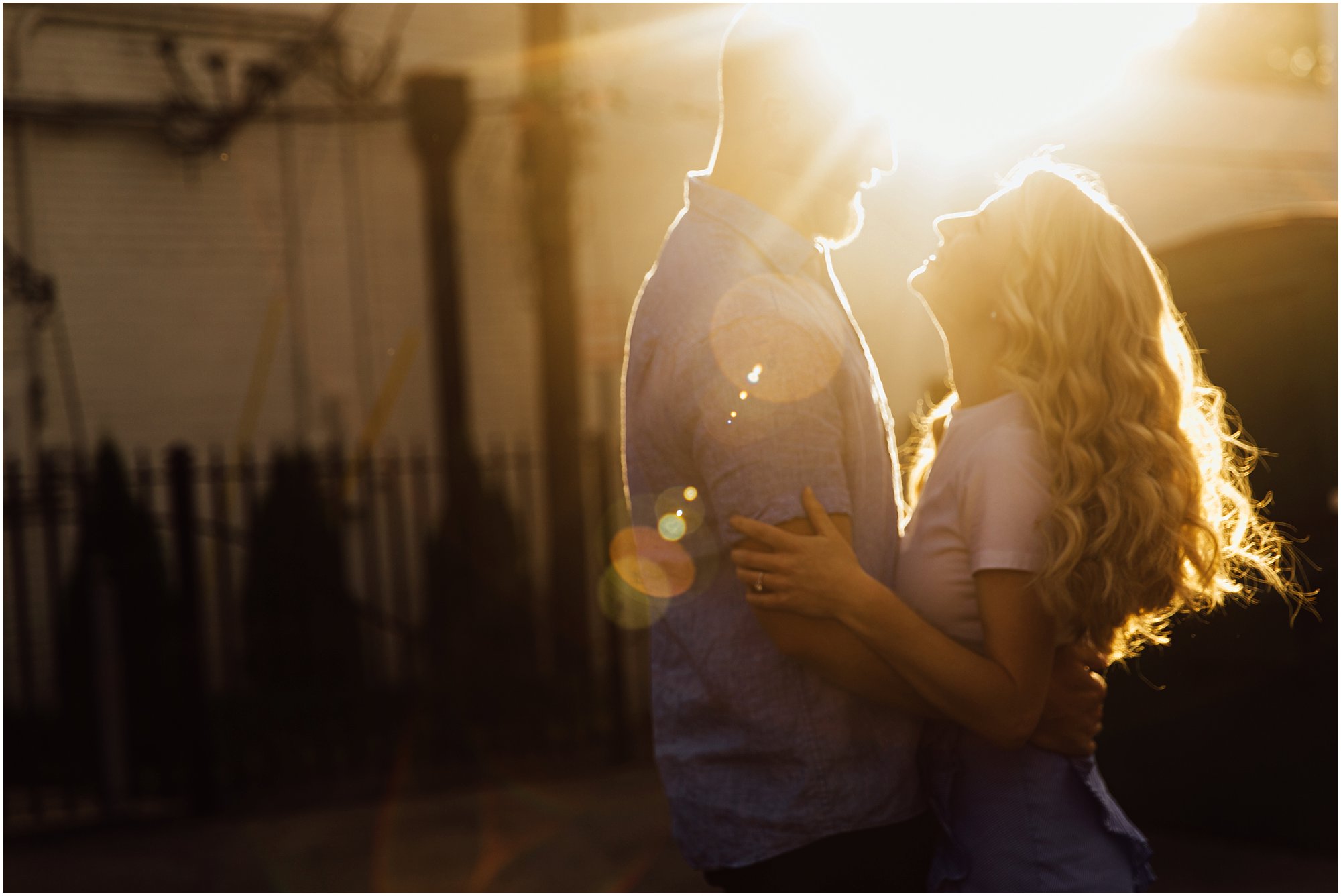 Lens flared image with couple romantically embracing at sunset