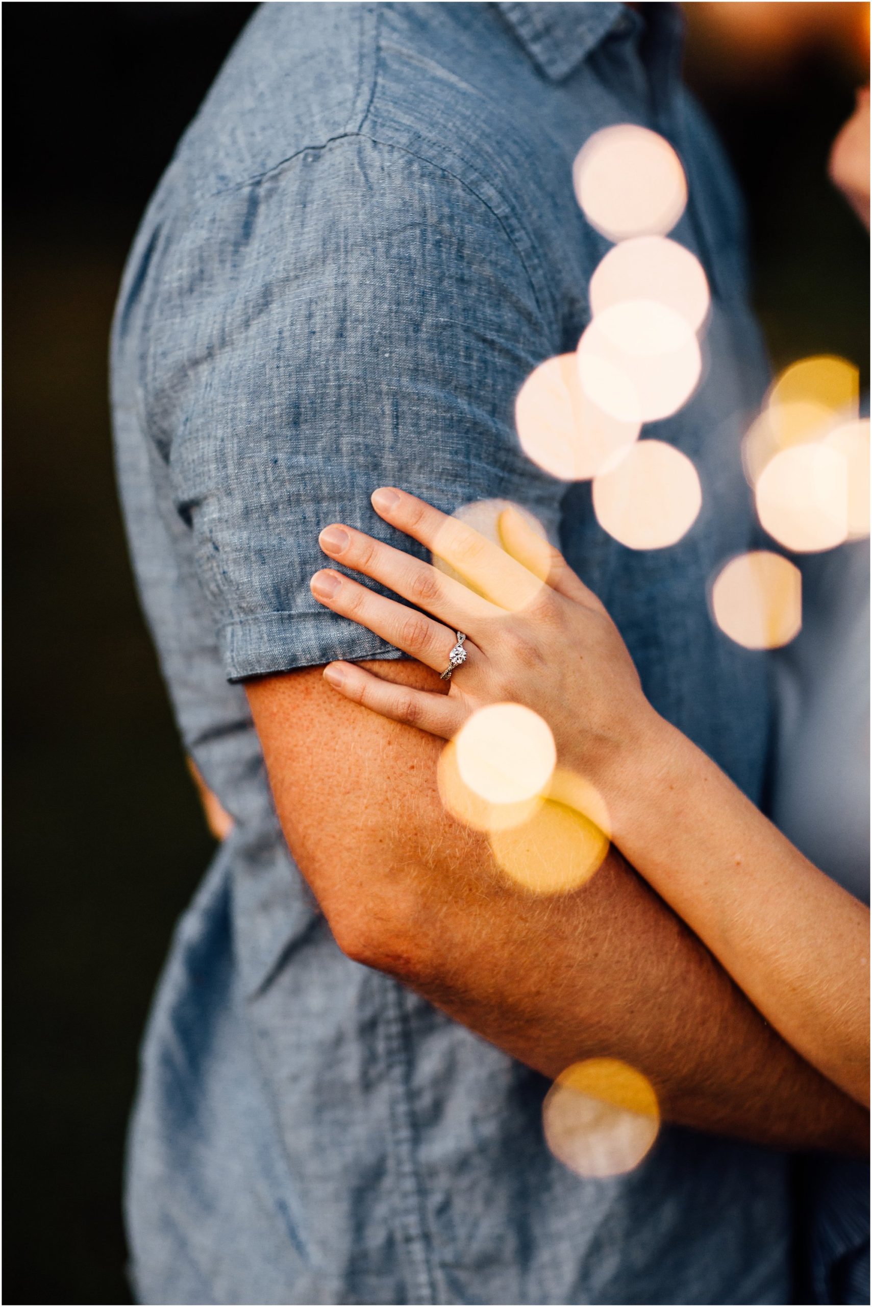 Close up of girl's hand with her engagement ring on it and bokeh lights surrounding